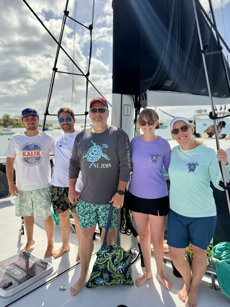 Five family members in sun shirts standing together on the deck of a sailboat in St. John